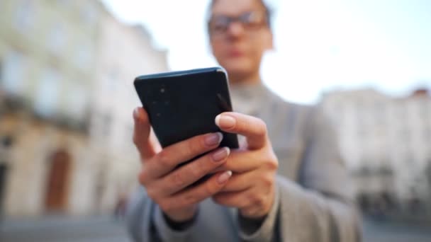 Mujer caminando por una calle vieja usando teléfono inteligente en. Primer plano. Comunicación, redes sociales, concepto de compras online. Movimiento lento — Vídeo de stock