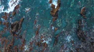 Issız bir sahil manzarası. Tenerife adasının kayalık kıyısı. Deniz dalgalarının kıyıya ulaşan hava aracı görüntüleri.