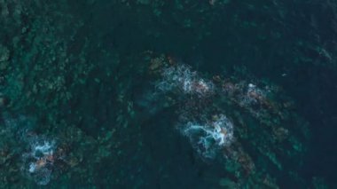 Issız bir sahil manzarası. Tenerife adasının kayalık kıyısı. Deniz dalgalarının kıyıya ulaşan hava aracı görüntüleri.