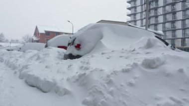 Kar fırtınasından sonra arabalar karla kaplandı. Arka plandaki konut binası..