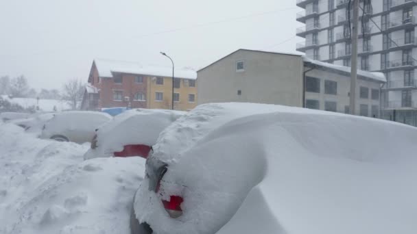 Coches cubiertos de nieve después de una ventisca de nieve. Edificio residencial en el fondo. — Vídeos de Stock