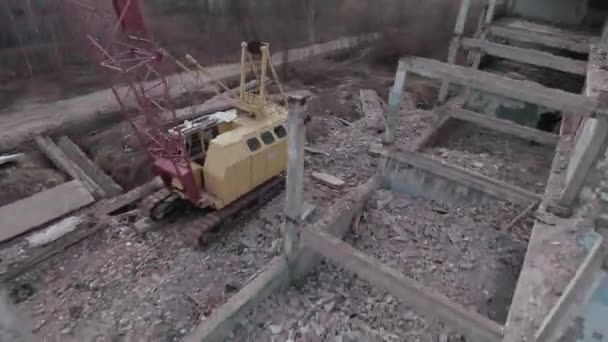 FPV drone flies quickly and maneuverable among abandoned industrial buildings and around an excavator. — Stock Video