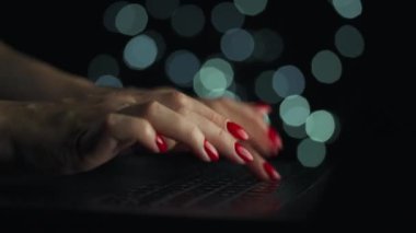 Hızlandırılmış kadın eli videosu gece bilgisayarda daktilo ediyor. Arka planda bulanık ışıklar var. Hızlı hareket. Zaman Uygulaması