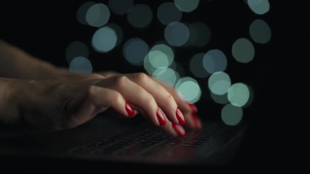 Le mani femminili stanno scrivendo su un portatile di notte. Luci sfocate sullo sfondo — Video Stock