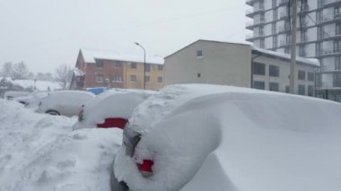 Kar fırtınasından sonra arabalar karla kaplandı. Arka plandaki konut binası..