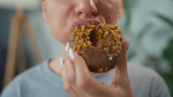 Kobieta jedząca czekoladowe pączki z karmelową posypką. Zbliżenie — Wideo stockowe