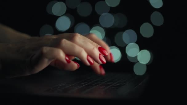 Las manos femeninas están escribiendo en un portátil por la noche. Luces borrosas en el fondo — Vídeo de stock