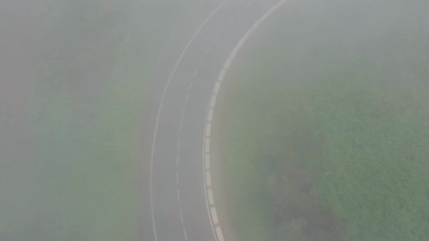 Volando a través de las nubes sobre un camino de montaña rodeado de vegetación verde. Conducción de coches en la carretera — Vídeo de stock