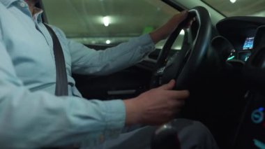 Adam yeraltı otoparkında araba sürüyor ve park edecek ya da gidecek bir yer arıyor. Yan görünüm