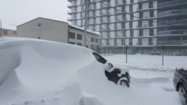 Kar fırtınasından sonra arabalar karla kaplandı. Arka plandaki konut binası..