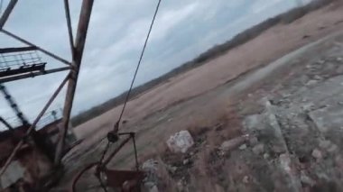 FPV insansız hava aracı, terk edilmiş paslı kazıcı yakınlarında manevra yapabilir.
