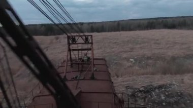 FPV insansız hava aracı, terk edilmiş paslı kazıcı yakınlarında manevra yapabilir.