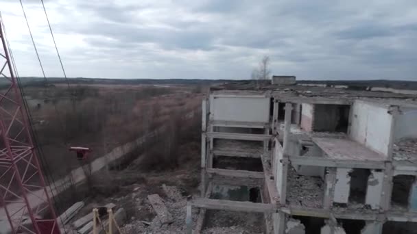 FPV drone vliegt snel en wendbaar tussen verlaten industriële gebouwen en rond een graafmachine. — Stockvideo