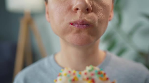 Kobieta jedząca słodkiego pączka w białej szkliwie z wielobarwnymi posypkami. Zbliżenie — Wideo stockowe