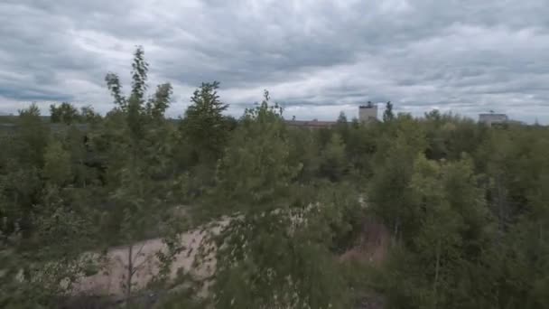 Le drone FPV vole rapidement et manœuvrable parmi les bâtiments industriels abandonnés et autour d'une pelle. — Video