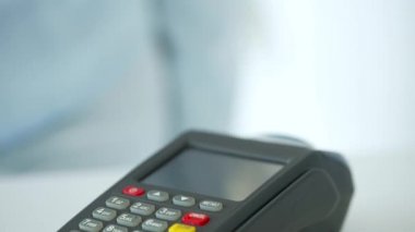 Akıllı telefondan yapılan temassız ödeme. Kablosuz ödeme konsepti. Yakın plan, kadın banka terminalindeki siparişi ödemek için akıllı telefon nakitsiz cüzdan teknolojisi kullanıyor..