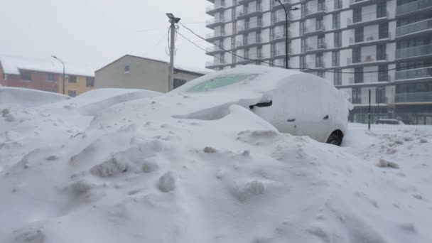 雪の吹雪の後に雪に覆われた車。バックグラウンドでの住宅建築. — ストック動画