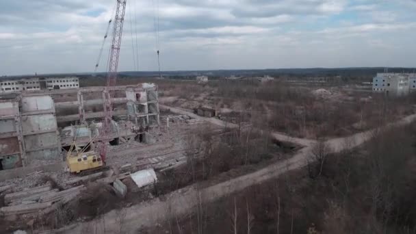 FPV drone vola rapidamente e manovrabile tra edifici industriali abbandonati e intorno a un escavatore. — Video Stock