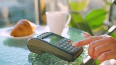 Akıllı telefondan yapılan temassız ödeme. Kablosuz ödeme konsepti. Yakın plan, kadın bir kafedeki banka terminalinin siparişini ödemek için akıllı telefon nakitsiz cüzdan teknolojisi kullanıyor..