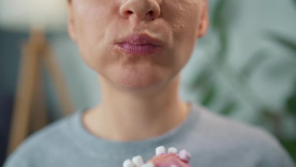 Kobieta jedząca słodkiego różowego pączka z piankami. Zbliżenie — Wideo stockowe