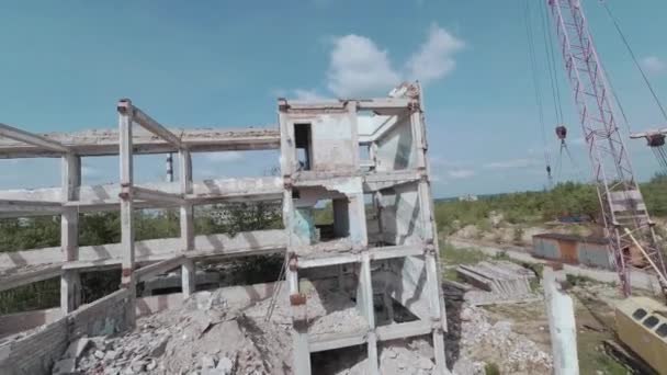 FPV drone vliegt snel en wendbaar tussen verlaten industriële gebouwen en rond een graafmachine. — Stockvideo