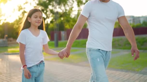日落时，爸爸和女儿在他们的地区散步。孩子牵着父亲的手。慢动作 — 图库视频影像