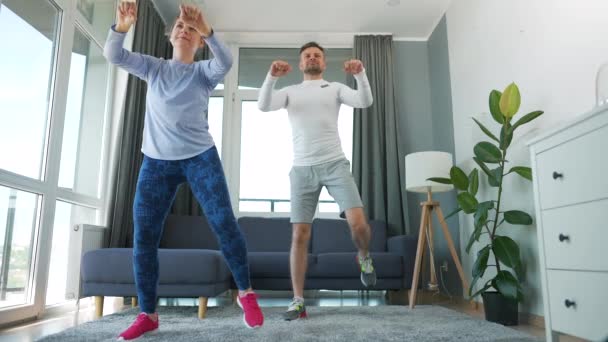 Caucásico pareja está haciendo ejercicio cardiovascular en casa en acogedora habitación luminosa, cámara lenta. — Vídeo de stock