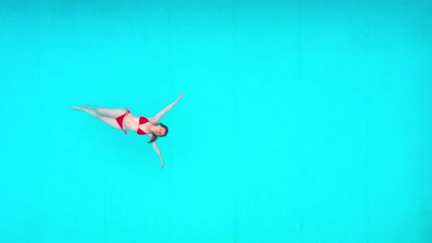 Blick von oben auf eine Frau im roten Badeanzug, die auf dem Rücken im Pool liegt. Entspanntes Konzept — Stockvideo