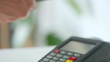 Akıllı telefondan yapılan temassız ödeme. Kablosuz ödeme konsepti. Yakın plan, kadın banka terminalindeki siparişi ödemek için akıllı telefon nakitsiz cüzdan teknolojisi kullanıyor..