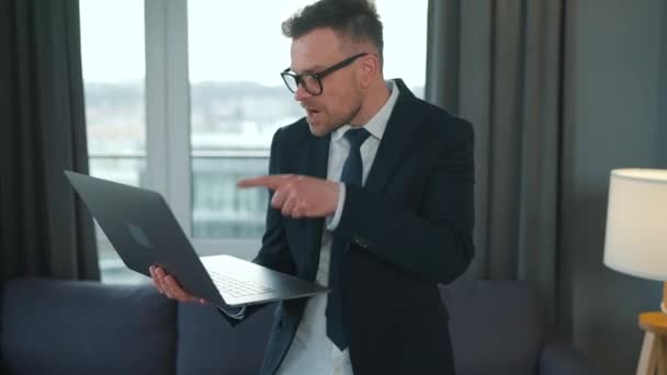 Biały mężczyzna ubrany w kurtkę i bieliznę, korzystający z laptopa, by wykonać wideo rozmowę z domu w nowoczesnym mieszkaniu. Zabawny film o zdalnej pracy — Wideo stockowe