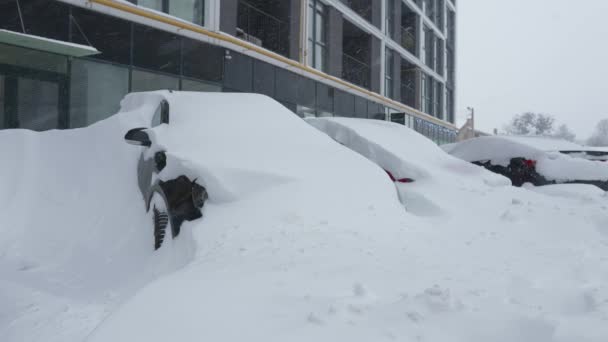 Mobil tertutup oleh salju setelah badai salju. Bangunan perumahan di latar belakang. — Stok Video