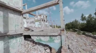 FPV insansız hava aracı, terk edilmiş sanayi binaları ve bir kazıcının etrafında hızla ve manevra kabiliyetiyle uçar..
