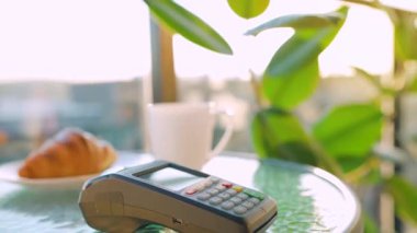 Akıllı telefondan yapılan temassız ödeme. Kablosuz ödeme konsepti. Yakın plan, kadın bir kafedeki banka terminalinin siparişini ödemek için akıllı telefon nakitsiz cüzdan teknolojisi kullanıyor..