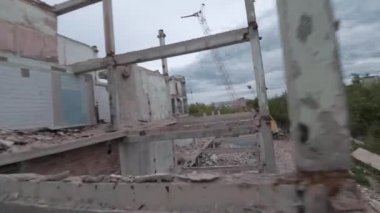 FPV insansız hava aracı, terk edilmiş sanayi binaları ve bir kazıcının etrafında hızla ve manevra kabiliyetiyle uçar..