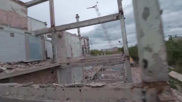 El dron FPV vuela rápido y maniobrable entre edificios industriales abandonados y alrededor de una excavadora. — Vídeos de Stock