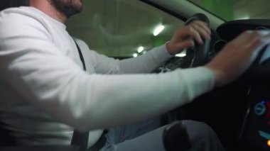 Adam yeraltı otoparkında araba sürüyor ve park edecek ya da gidecek bir yer arıyor. Yan görünüm