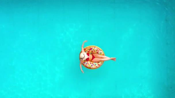 Вид с воздуха на женщину в красном бикини, лежащую на пончике в бассейне — стоковое видео