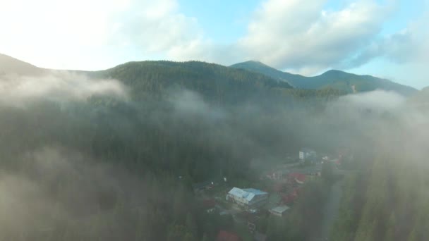 Volo sopra una località montana tra la foresta di conifere. Nebbia sorge sopra i pendii della montagna — Video Stock