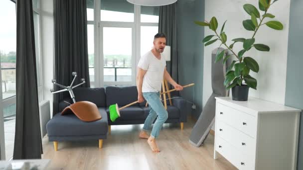 Pria membersihkan rumah dan bersenang-senang menari dengan sapu. Gerakan lambat — Stok Video