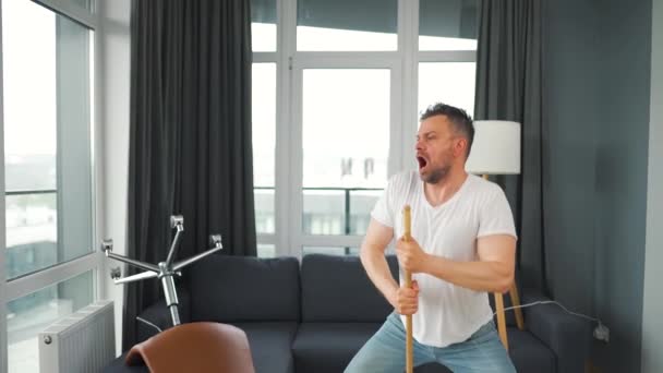 Hombre limpiando la casa y divirtiéndose bailando y cantando con una escoba. Movimiento lento — Vídeo de stock