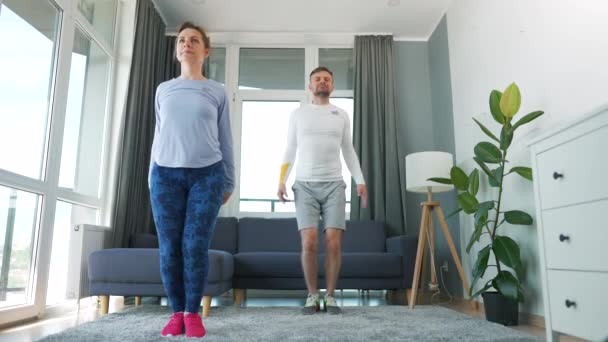 Kavkazský pár dělá skákání jacks cvičení doma v útulné světlé místnosti, zpomalení. — Stock video