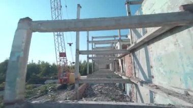 FPV insansız hava aracı, terk edilmiş sanayi binaları ve bir kazıcının etrafında hızla ve manevra kabiliyetiyle uçar..