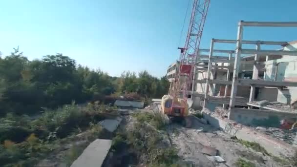 FPV drone flies quickly and maneuverable among abandoned industrial buildings and around an excavator. — Stock Video