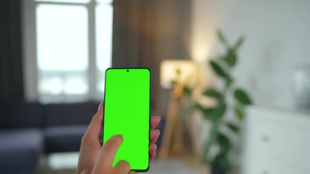 Γυναίκα στο σπίτι χρησιμοποιώντας smartphone με πράσινη οθόνη mock-up σε κάθετη λειτουργία. Κορίτσι περιήγηση στο Internet, βλέποντας περιεχόμενο, βίντεο. POV. — Αρχείο Βίντεο