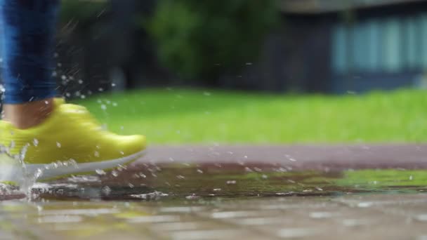 Femme sportive faisant du jogging à l'extérieur, entrant dans la flaque d'eau. Un seul coureur court sous la pluie, faisant des éclaboussures. Mouvement lent — Video