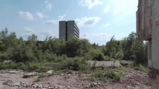 FPV drone vliegt snel en wendbaar tussen verlaten industriële gebouwen en rond een graafmachine. — Stockvideo