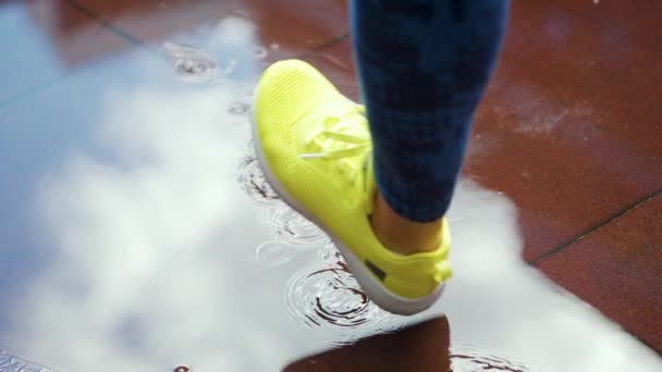Mujer deportista corriendo al aire libre, entrando en el charco. Un solo corredor corriendo bajo la lluvia, haciendo chapoteo. Movimiento lento — Vídeo de stock