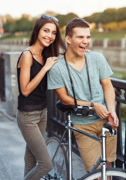 Happy couple - man and woman with bike in the park outdoor — Stock Photo, Image