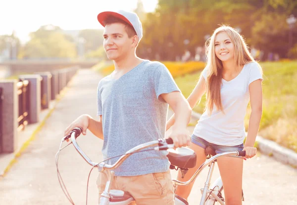 Pareja feliz - hombre y mujer montando una bicicleta en el parque al aire libre — Foto de Stock