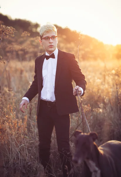 Young attractive man in suit and tie with a greyhound dog in aut — Stock Photo, Image